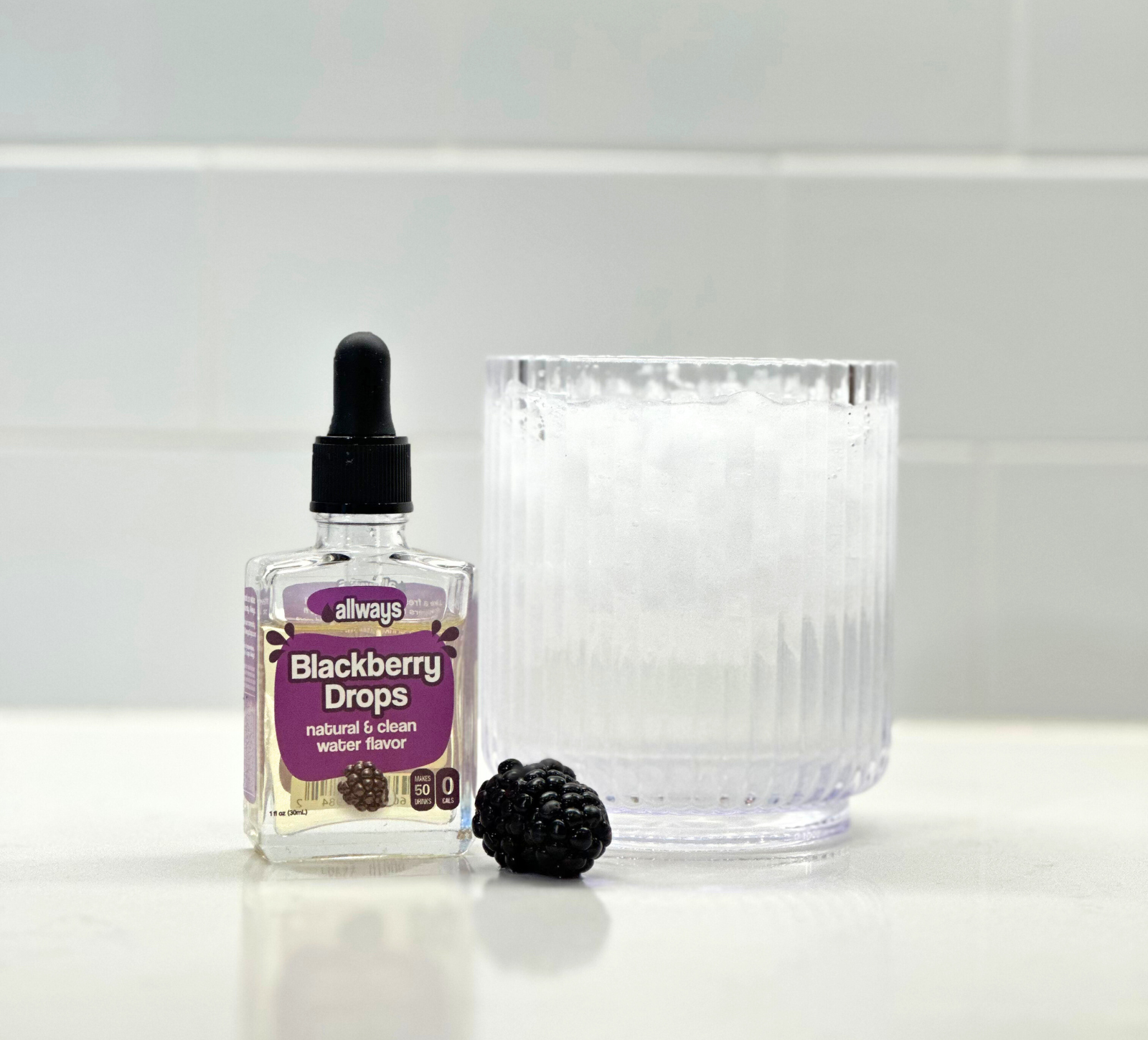 Allways Blackberry Drops in front of an ice cold refreshing, hydrating glass of water with fresh blackberry