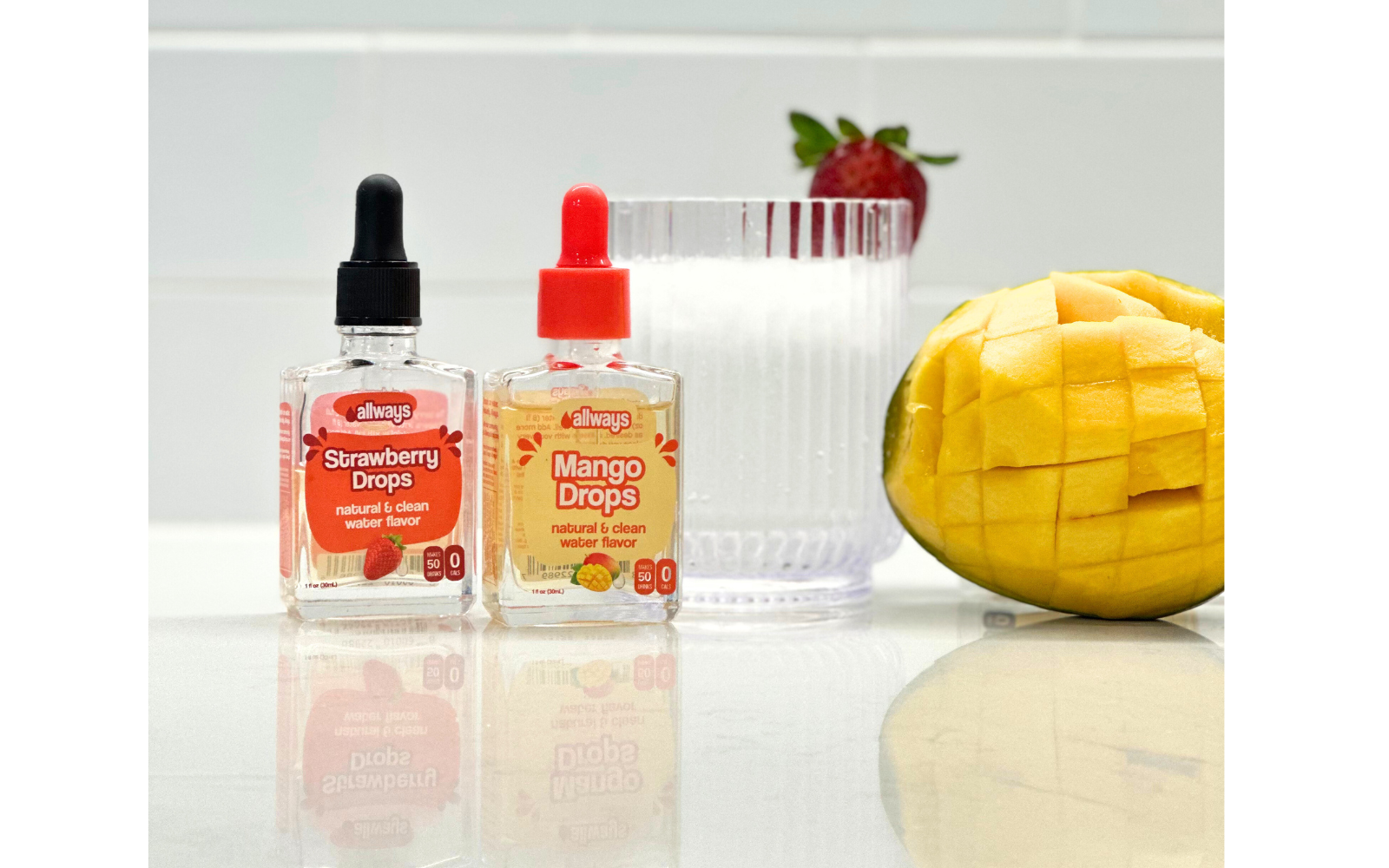 Allways Strawberry Drops and Mango Drops in front of a fresh mango and strawberry drink