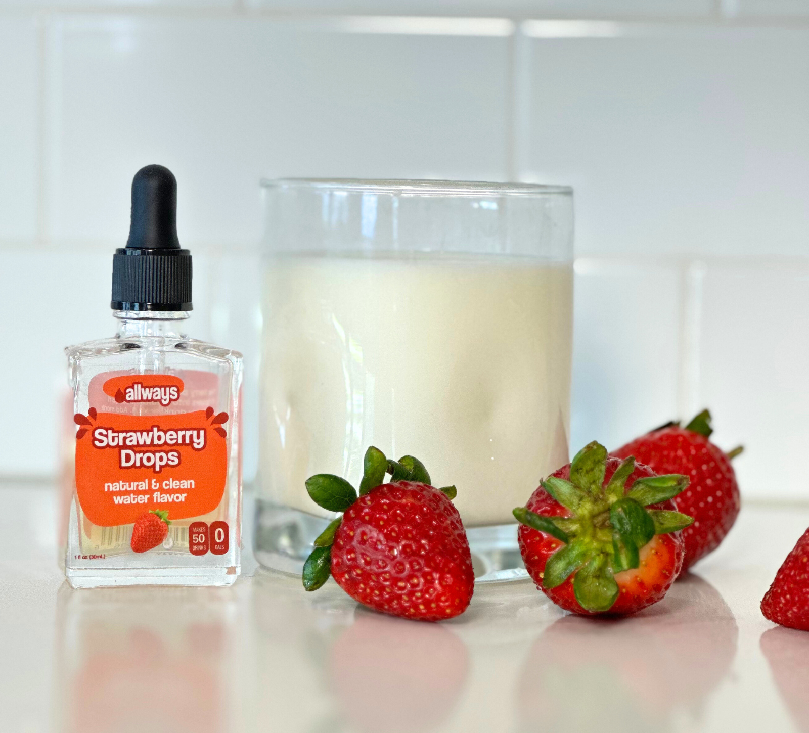 Allways Strawberry Drops in front of a refreshing glass of milk with fresh strawberries
