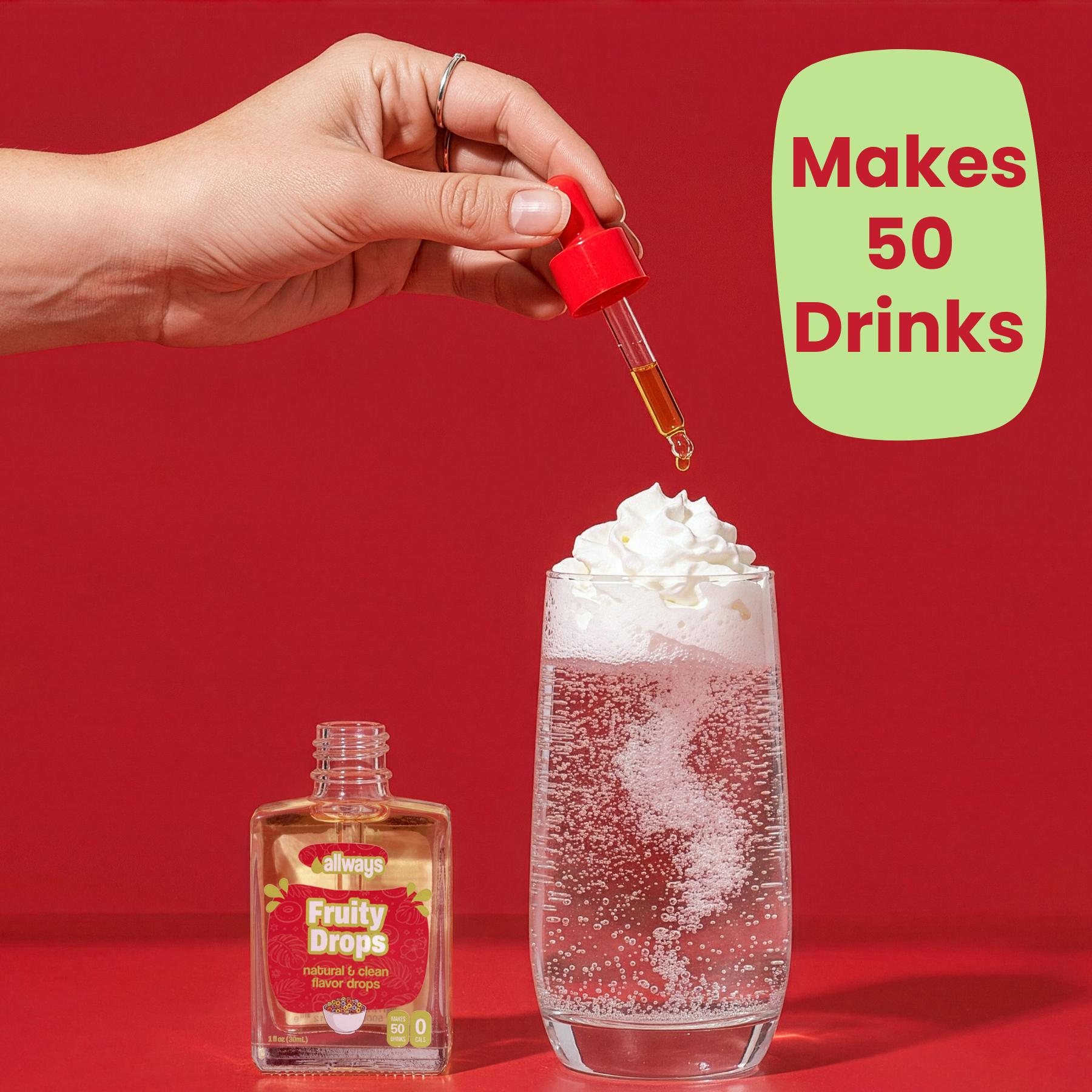 Hand using a dropper to add liquid from 'Fruity Drops' bottle into a glass with whipped cream and bubbles on a red background.