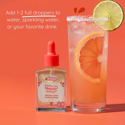 Allways Paloma Drops bottle with a glass of paloma mocktail and lime and grapefruit slice on an grapefruit colored background