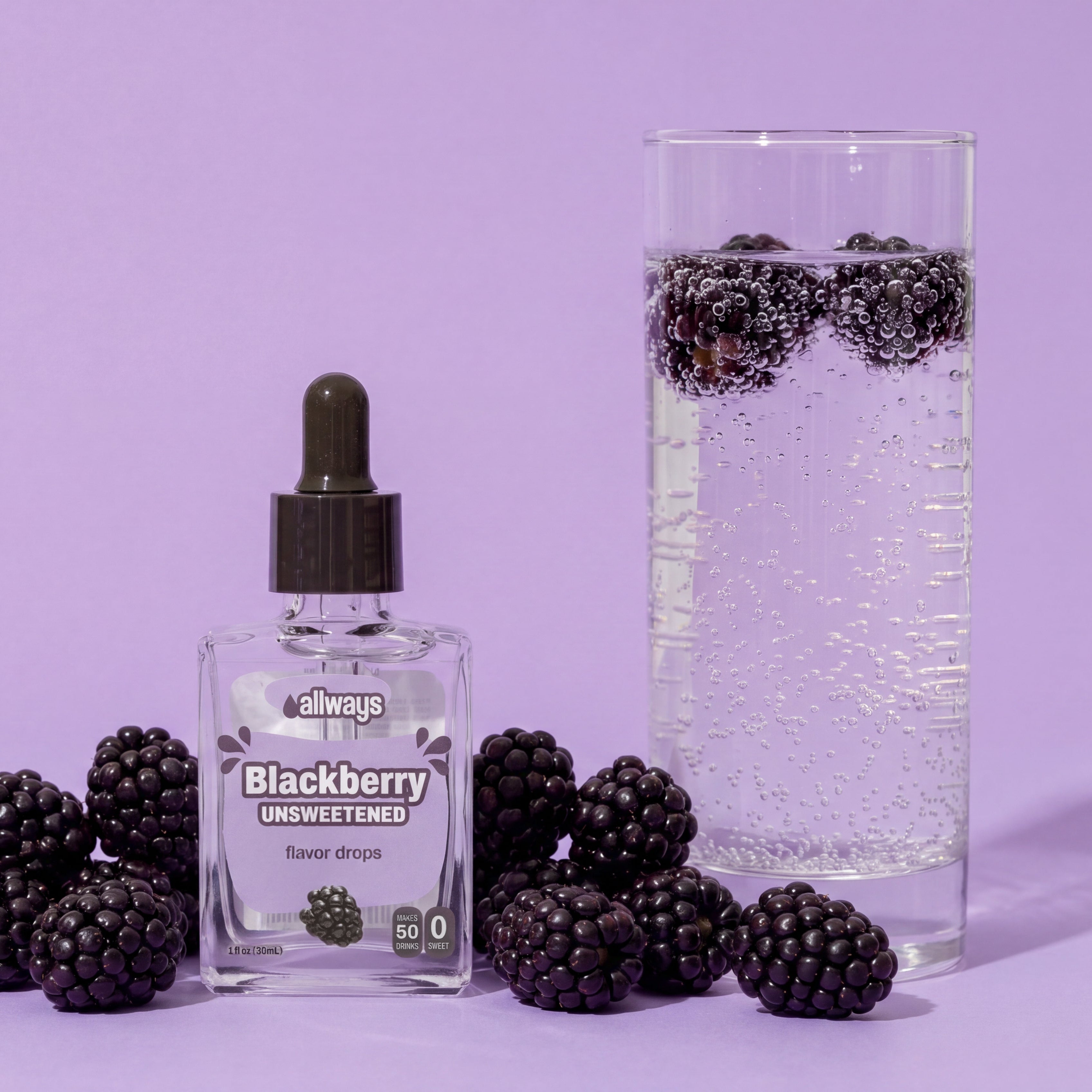 A bottle of Always Blackberry Lemonade flavor drops sits on a lavender background, surrounded by fresh blackberries and next to a tall glass of sparkling water with blackberries floating in it.