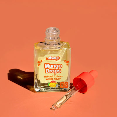 Allways Mango Drops with dropper laying next to a glass bottle of Mango Drops in front of a orange backdrop
