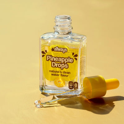 Allways Pineapple Drops in a glass bottle with dropper laying next to it in front of a yellow background